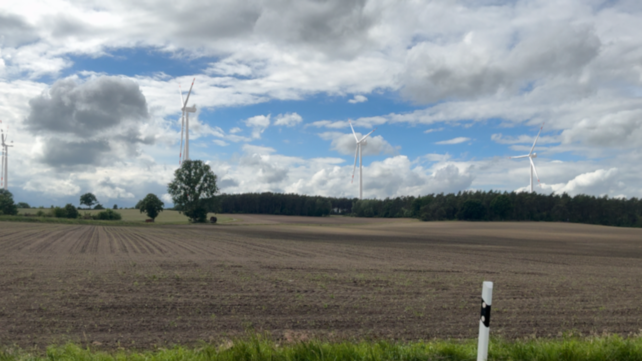 Acker mit Windenergieanlage am Horizont