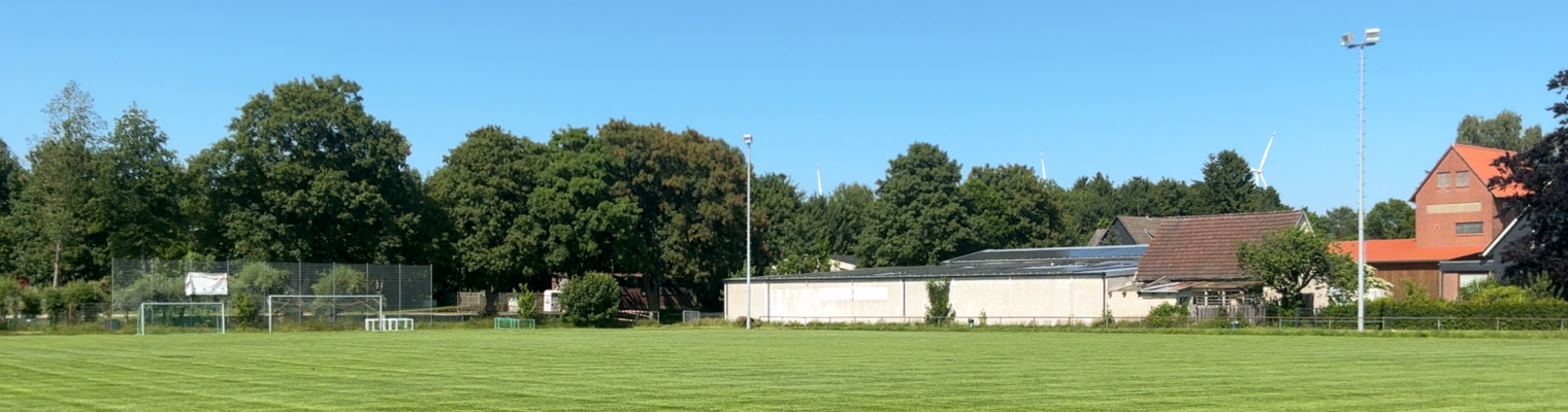 Sportplatz Zernien mit Windenergieanlagen sichtbar hinter den Hecken am Horizont.